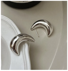Macro detail of silver moon-shaped studs featuring a polished finish on ceramic