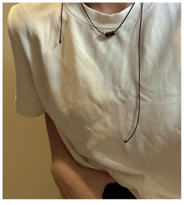 Detail of S925 silver cylinder pendant on minimalist black cord necklace against white T-shirt