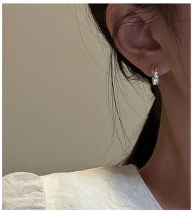 Close-up of S925 silver huggie earrings with textured hammered finish on a model