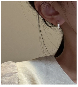 Detail of S925 sterling silver earrings with irregular hammered texture on a model