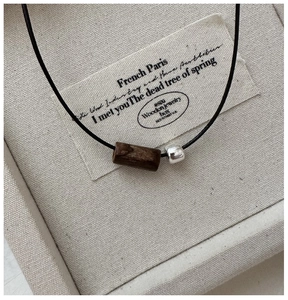 Close-up of S925 silver square bead and cylindrical wood pendant on black cord necklace