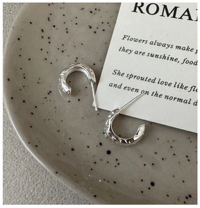 Close-up of S925 sterling silver C-shaped earrings with irregular hammered lava texture