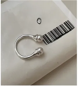 Macro detail of S925 sterling silver horseshoe open ring featuring twin white pearls
