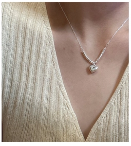 Close-up of S925 silver heart pendant necklace with laser beads on a beige knit sweater
