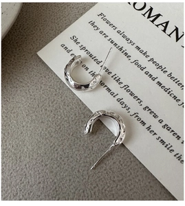 Macro detail of silver S925 sterling silver earrings with irregular hammered texture