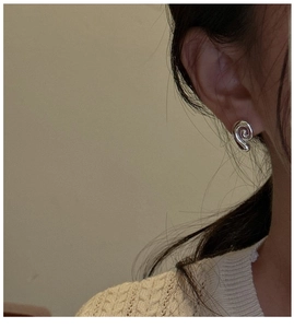 Close-up of a minimalist silver spiral conch earring worn on a model's ear