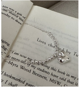 Macro detail of S925 sterling silver heart necklace with laser beads on book pages