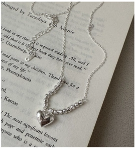 Macro detail of S925 sterling silver heart necklace with beads on a vintage book