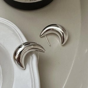 Polished S925 sterling silver crescent moon hoop earrings on a white ceramic tray