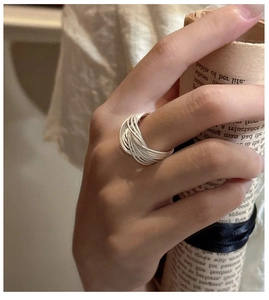 Détail d'une bague multi-rangs en argent S925 portée sur fond de papier vintage rétro