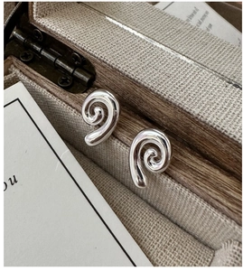 Macro shot of silver spiral shell stud earrings resting in a vintage jewelry box