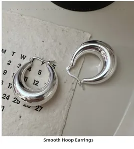 Close-up of chunky S925 sterling silver C-shaped hoop earrings with a high-polished finish