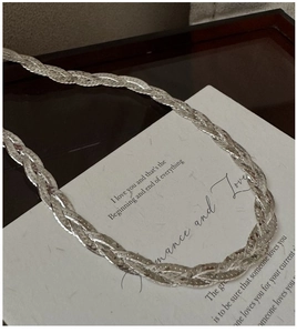 Macro shot of silver triple-layered braided snake chain necklace with high-gloss finish