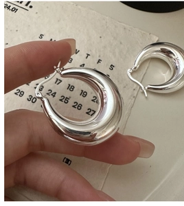 Macro detail of S925 sterling silver U-shaped hoop earrings with clear 925 hallmark stamp