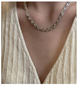 Close-up of triple-layered silver braided chain necklace worn on a beige knit sweater