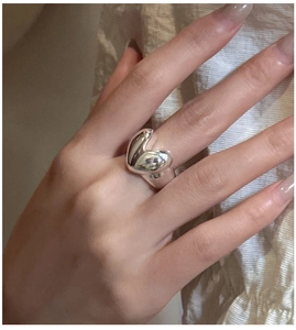 Close-up of a chunky heart-shaped sterling silver ring worn on index finger