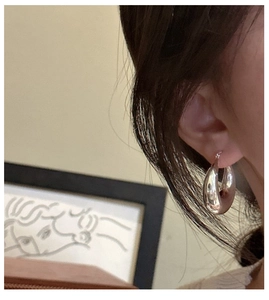 Detail view of large teardrop silver hoop earrings worn for a minimalist chic style