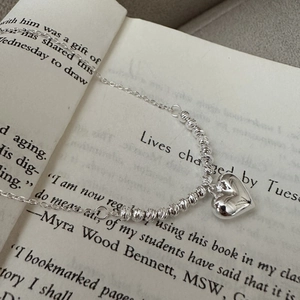 Classic S925 sterling silver heart pendant necklace with laser textured beads on a book