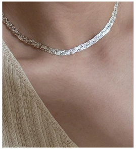 Detail view of a triple-layered S925 sterling silver woven necklace on a model's neck