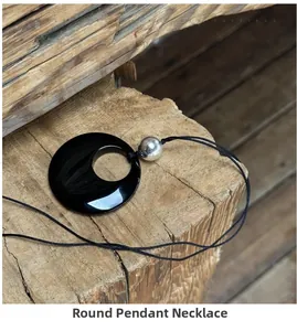 Macro view of a 50mm black obsidian pendant necklace resting on natural wood texture