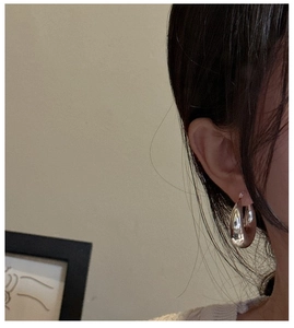 Close-up of polished thick silver hoop earrings worn by a model for a stylish look