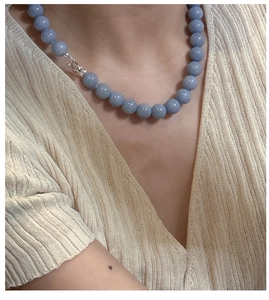 Detail of blue beaded sterling silver necklace worn on a beige knit sweater