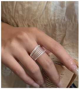 Detail of layered S925 silver rings with polished bands and twisted rope textures on hand