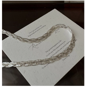 Macro shot of S925 sterling silver three-layer braided chain necklace on a card