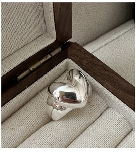 Macro shot of chunky polished S925 sterling silver heart ring in a luxury walnut box