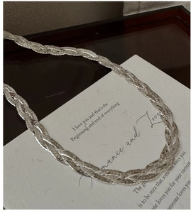 Close-up of triple-layered braided silver snake chain necklace with flat weave texture