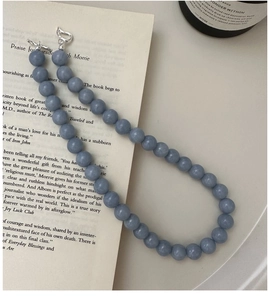 Detail of light blue beaded necklace with silver toggle clasp on a book background