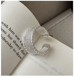 Close-up of S925 sterling silver multi-layer textured ring on an open book background