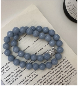 Detail view of blue stone beaded necklace with elegant silver clasp on an open book