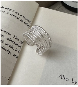 Macro detail of multi-layer twisted rope S925 silver ring on an open book background
