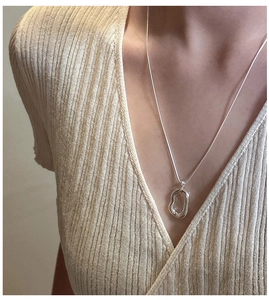 Close-up of polished S925 sterling silver organic oval pendant on a fine chain necklace