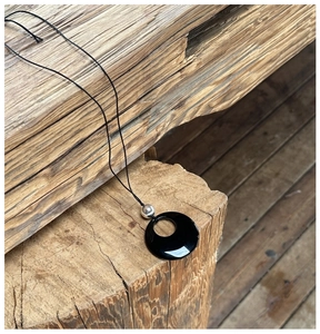 Minimalist S925 silver necklace with black obsidian ring pendant on natural wood background