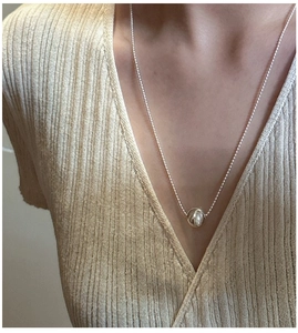 Close-up of minimalist S925 sterling silver necklace with a polished bead on a model