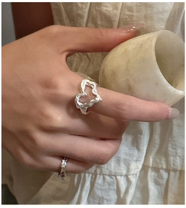 Detail of S925 silver lava heart ring and wavy band with molten texture on female hand