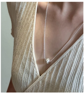 Detail of polished S925 sterling silver ball pendant necklace on a female model