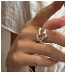 Detail of S925 silver heart ring with irregular lava texture worn on the finger