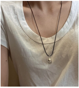 Detail of minimalist S925 sterling silver ball pendant on a slim black rope necklace
