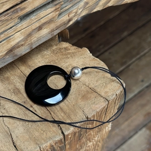 S925 silver necklace with black obsidian disc pendant displayed on a rustic wood block