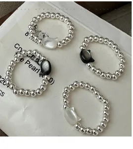 Detailed view of elastic S925 silver beaded rings with black and white cat shell charms