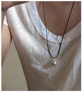 Detail of minimalist S925 silver frosted ball pendant on a simple black cord necklace