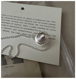 Macro shot of S925 silver beaded necklace with textured spherical pendant on vintage card