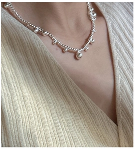 Detail of S925 sterling silver beaded necklace with round pendants on a model's neck