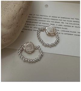 Detail of beaded silver rings with white mother-of-pearl rose flowers on a stone base
