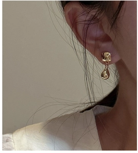Detail of gold geometric earrings featuring hammered square studs and teardrop pendants