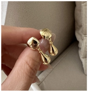 Close-up of golden S925 sterling silver drop earrings with geometric square studs