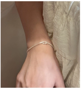 Nahaufnahme eines minimalistischen S925 Sterling Silber Doppelknoten-Schlangenarmbands